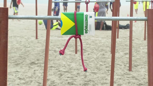 Jovens se penduram em paus de arara em ato de valorização da democracia na Praia de&nbsp;Copacabana